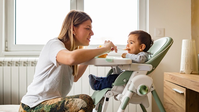 woman feeding baby in a high chair